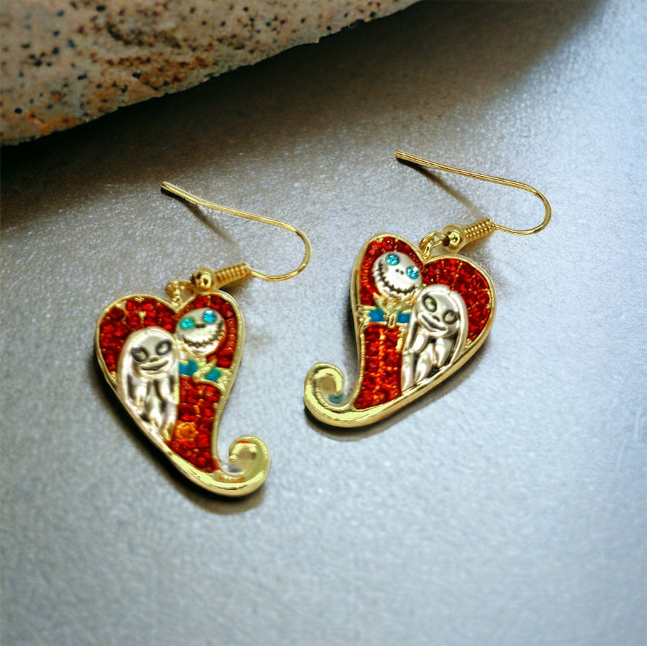 A pair of red and gold colored earrings featuring characters from 'The Nightmare Before Christmas' on a textured surface.