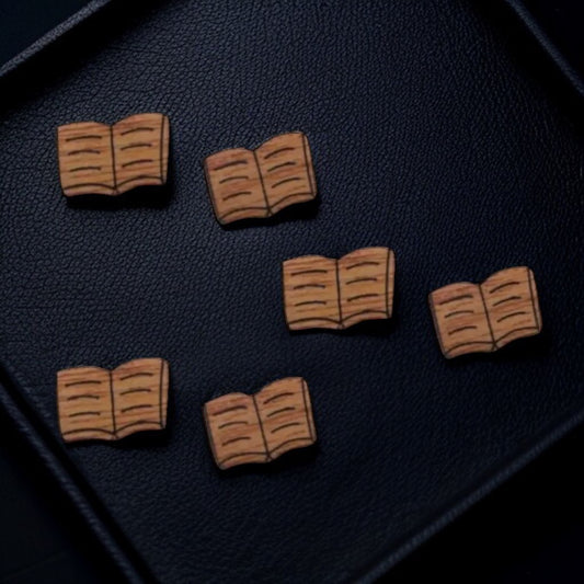 Wooden book-shaped pins on a dark textured surface