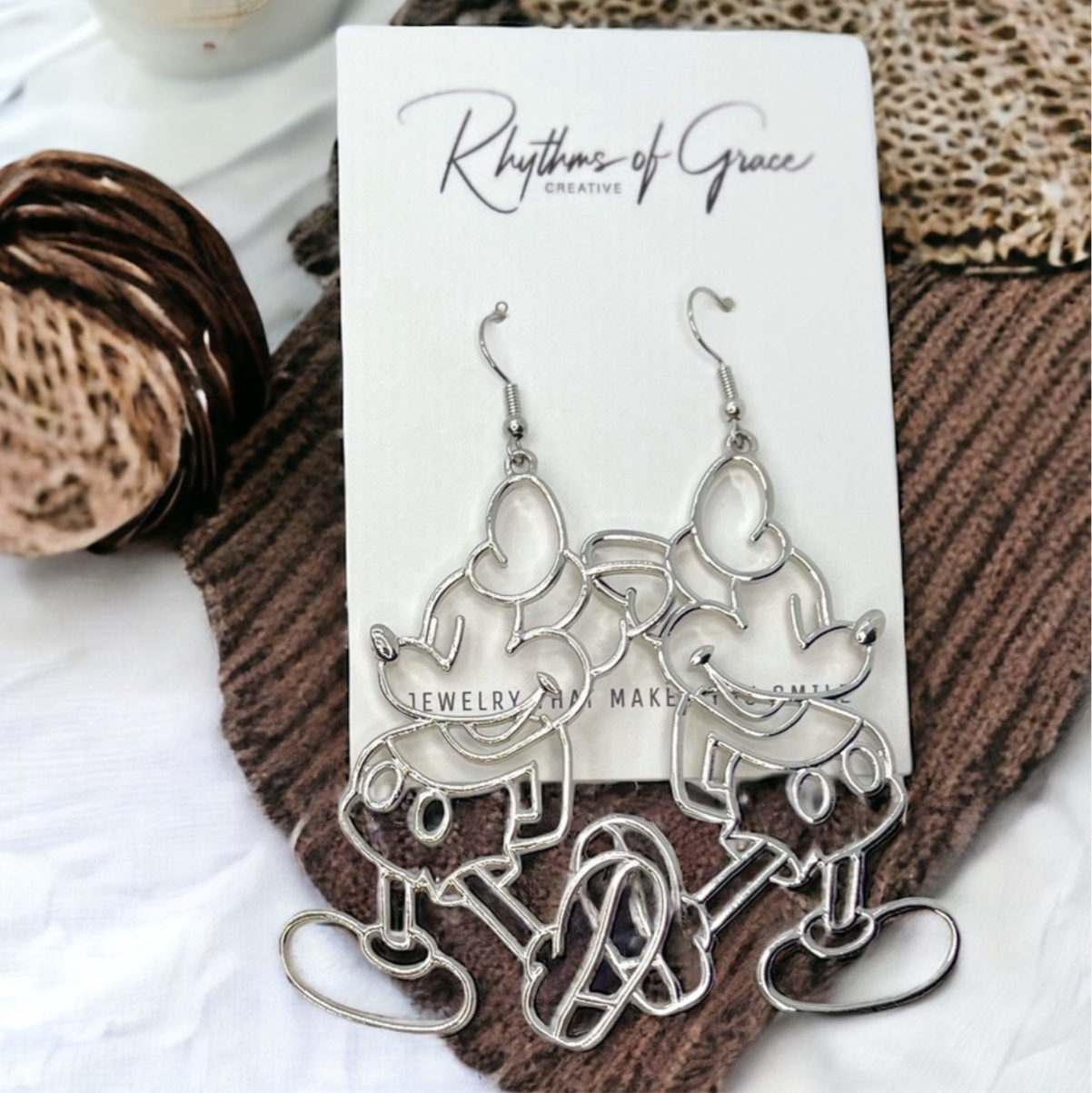 Silver earrings on a card with a textured surface background