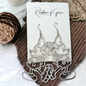 Silver earrings on a card with a textured surface background