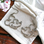 Pair of silver Mickey Mouse earrings on a white cloth with a wooden surface underneath.