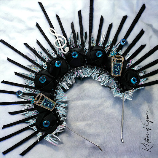 A handmade jazz fest headpiece featuring music-themed accents such as notes and guitars, with a predominantly black and silver color scheme.