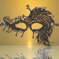 A black lace masquerade mask with intricate patterns, displayed against a yellow background. The mask is designed with a tie-back style for wearing.