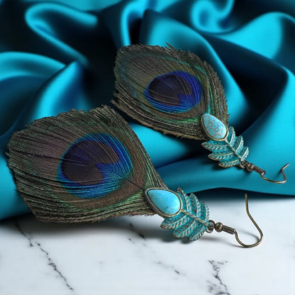 Peacock feather earrings with turquoise stones on a blue satin background