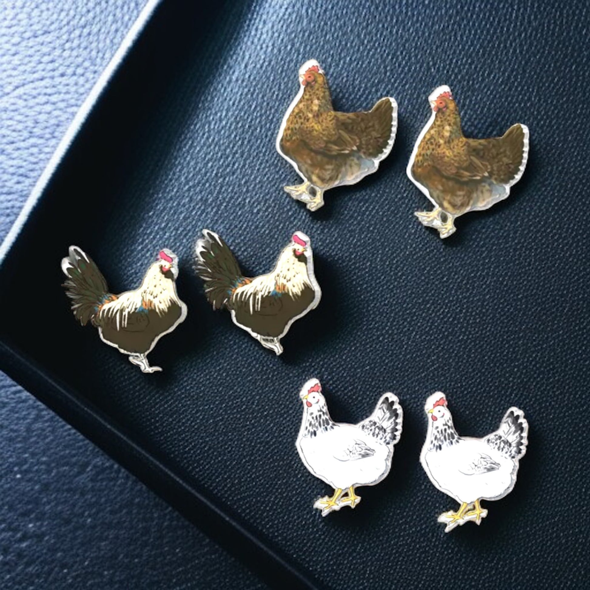 Set of chicken-shaped pins on a dark blue surface