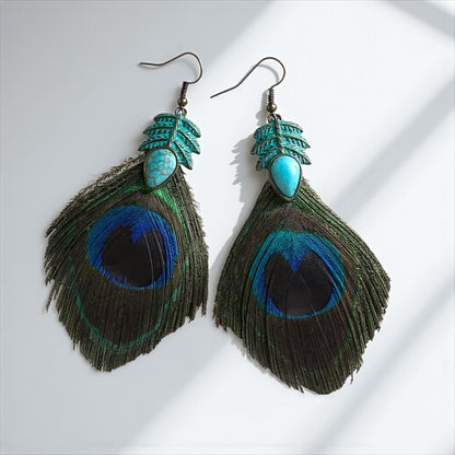 Pair of peacock feather earrings with turquoise accents on a white background
