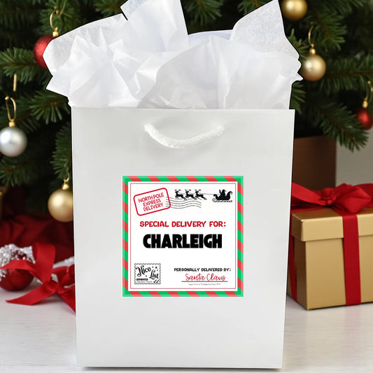 White gift bag with personalized label in front of a decorated Christmas tree